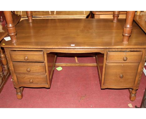 An Ercol mid elm 'Golden Dawn' kneehole desk having an arrangement of five drawers, width 137cm