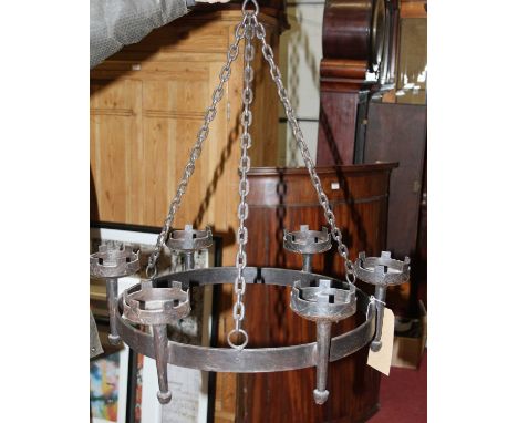 A black painted wrought iron hanging ceiling light, suspended from chains, with six torchere shaped candle holders, dia.56.5c