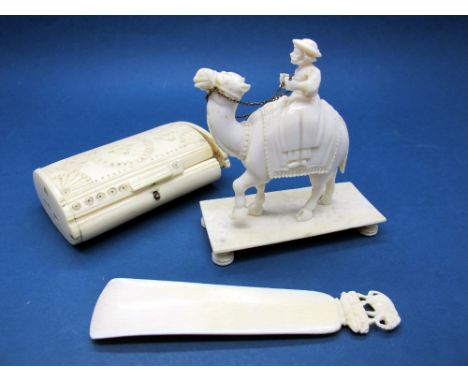 An Early XX Century Ivory Model of a Gentleman Riding a Camel, rectangular base, 8.5cms high; An African Ivory Shoe Horn, wit