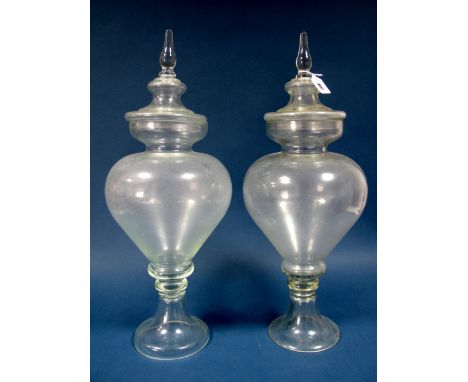 A Pair of Late Victorian Clear Glass Apothecary Bottles, each of footed circular section, the lift-off covers with spike fini