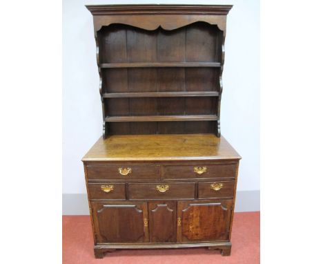 An XVIII Century Oak Dresser, the rack with stepped pediment and shaped cornice above three shelves to panelled back, the bas