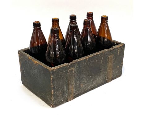 A vintage crate containing eight brown glass bottles