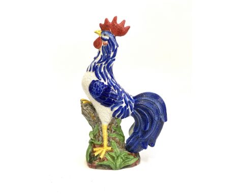 A large continental ceramic figure of a cockerel standing on a tree stump, 57cmH