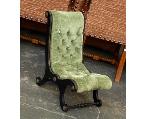 A 19th century ebonised button back cross frame slipper chair, with applied metal rosettes
