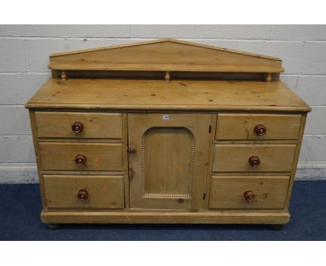 A VICTORIAN PINE SIDEBOARD with a raised back and shelf, above two banks of three drawers flanking a single cupboard door, la