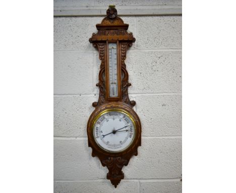A LATE VICTORIAN CARVED OAK ANEROID BAROMETER, with mercury thermometer and working blued indicator, height 90.5cm