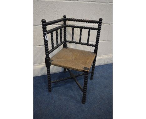 AN EARLY 20TH CENTURY EBONISED ARTS AND CRAFTS BOBBIN TURNED CORNER CHAIR with a rush seat