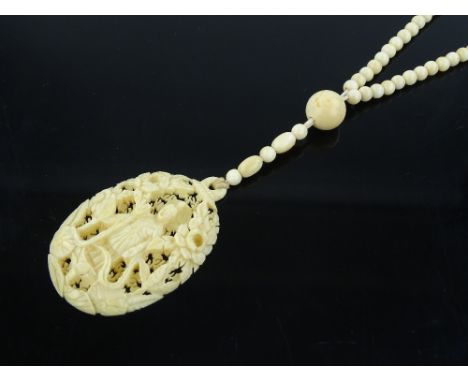 A Chinese relief carved and pierced ivory Buddha design pendant, length 56mm on ivory bead chain.