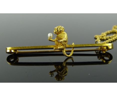 An Edwardian 15ct gold monkey design bar brooch, holding a small pearl, length 48mm, 4.8g.