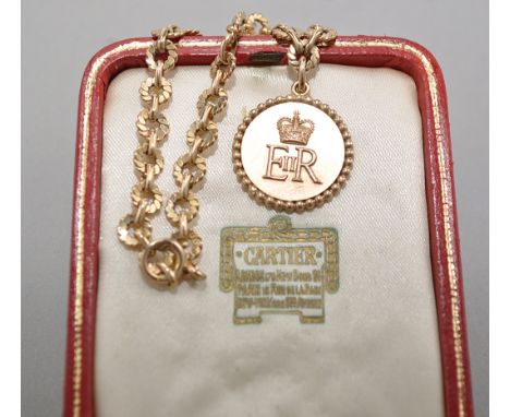 A gift from Her Majesty Queen Elizabeth II, Cartier, Paris: a 9ct. yellow gold circular pendant, with Royal cipher within bea