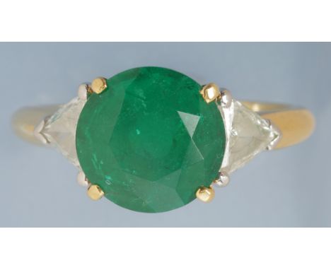 An emerald and diamond ring, the circular facet cut emerald measuring 10.3 x 10.3 x 7.1mm, estimated to weigh 3.75 carats, fl