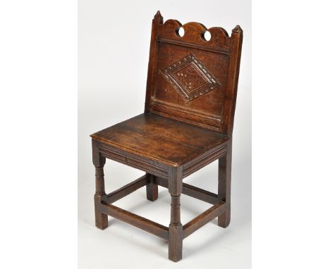 An 18th Century joined oak Lancashire chair, the shaped back above carved diamond-decorated panel, solid seat under raised on