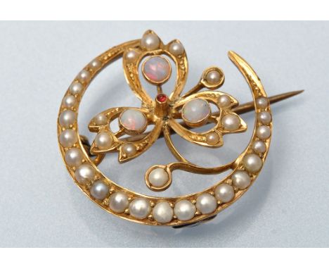 A half pearl opal and ruby crescent form brooch, centred by shamrock with small ruby cabouchon, surrounded by three circular 