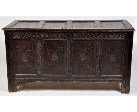 An 18th Century oak coffer, the plain panel top above flowerhead and scroll decorated frieze, three carved roundel pattern pa