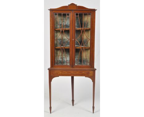 An Edwardian inlaid mahogany corner display cabinet on stand, fitted a pair of glazed panel doors enclosing velvet lined inte