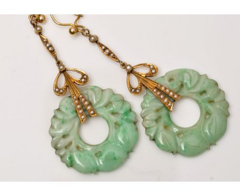 A pair of Edwardian carved jade and seed pearl drop earrings, each with main circular jade stone carved with fruit, hanging f