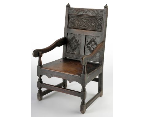 A late 17th Century joined oak open armchair, the panel back with diamond motifs and acanthus scrolls, flanked by shaped arms