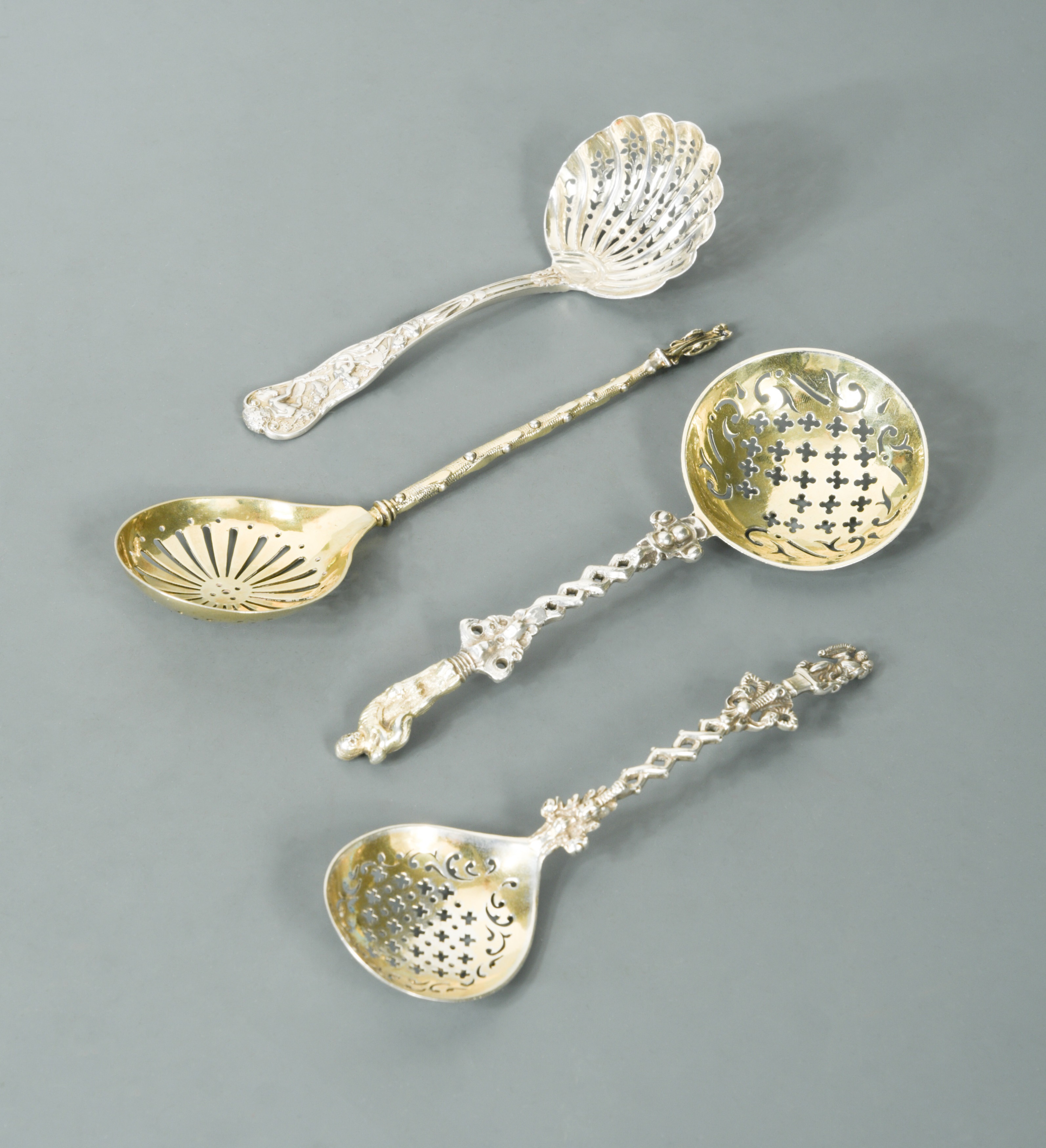 A collection of four Victorian silver novelty sugar sifting spoons, in