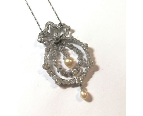 garland style, topped with an openwork diamond set ribbon and bow with a central rubover set old mine cut diamond, estimated 
