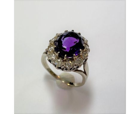 central claw set oval faceted amethyst of rich purple, surrounded by a border of twelve round brilliant cut diamonds, estimat