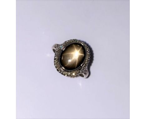 central oval cabochon chocolate brown/black sapphire, 13.7 x 11.1mm, estimated approximate weight 7.90ct, displaying asterism