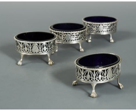both pairs of oval form with each with decorated pierced sides and gadrooned rim, with blue glass liners and raised on four b