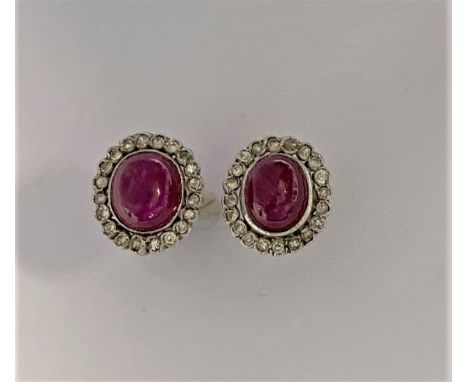 each with a central oval cabochon ruby, approximately 7.8 x 6.6mm, surrounded by a border of twenty rubover set eight cut dia