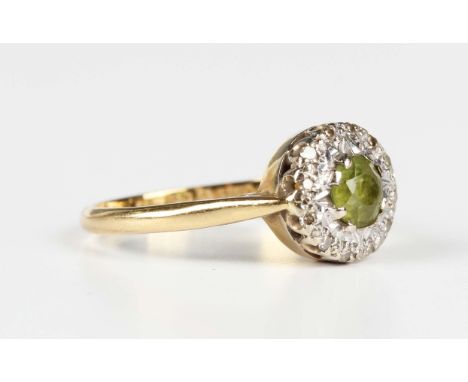 An 18ct gold, peridot and diamond cluster ring, claw set with the circular cut peridot within a surround of circular cut diam