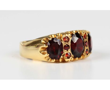A gold and garnet ring, mounted with the three principal oval cut garnets alternating with two rows of three smaller circular