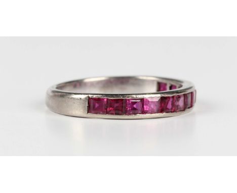 A ruby half eternity ring, mounted with a row of square cut rubies, unmarked, weight 4.6g, ring size approx S.Buyer’s Premium