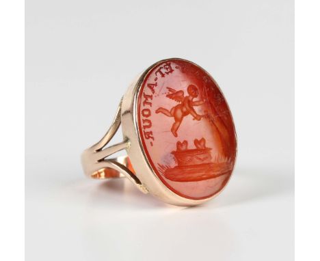 A gold ring, collet set with an oval cornelian intaglio, detailed 'Le.Pas.Et.Amour' above a cherub, unmarked, weight 6.7g, ri