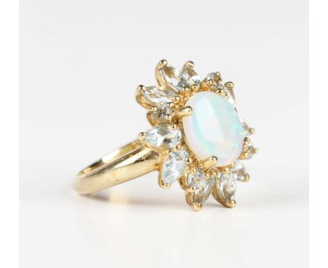 A 9ct gold, opal and blue gem set cluster ring, claw set with the oval opal within a surround of variously cut blue gemstones