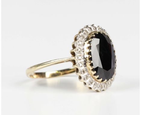 A 9ct gold, sapphire and diamond oval cluster ring, claw set with the oval cut sapphire within a surround of circular cut dia