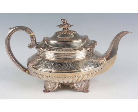 A George IV silver teapot of squat oval half reeded form, the hinged lid with acorn and oak leaf finial above a cast foliate 