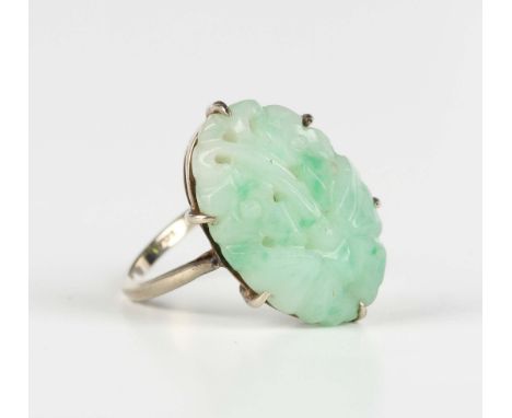 A white gold ring, claw set with an oval jade with carved and pierced decoration, detailed '9ct', weight 4.2g, ring size appr
