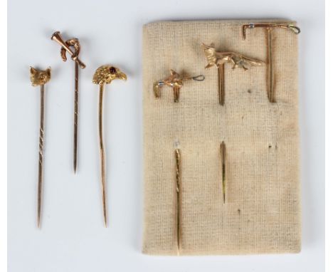 Four gold hunting themed stickpins, comprising a standing fox, a riding crop with a fox's mask motif with diamond set eyes, a