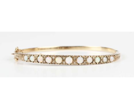 A gold, opal and diamond oval hinged bangle, the front mounted with a graduated row of cabochon opals alternating with pairs 