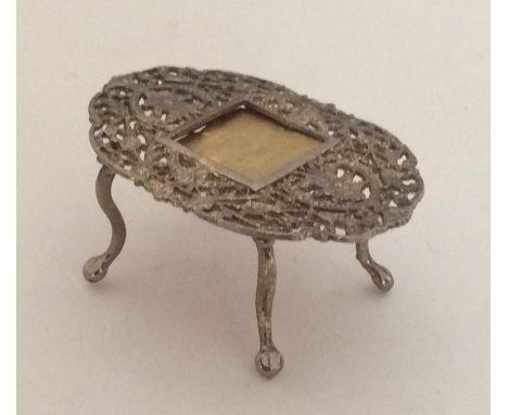 A small silver filigree doll's house table with central frame. Approx. 22 grams. Est. £15 - £20.