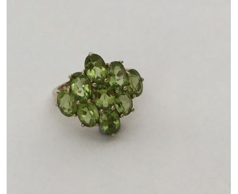 A large 9 carat peridot cluster ring in gold mount. Approx. 4 grams. Est. £60 - £80.