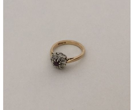 A ruby and diamond circular cluster ring in 9 carat two colour gold. Approx. 2.9 grams. Est. £30 - £40.