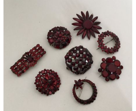 A collection of eight red Vauxhall glass brooches. Est. £150 - £200.