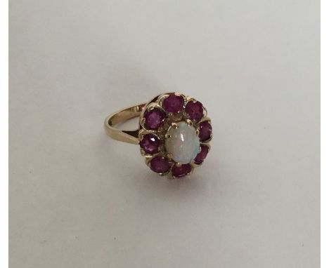 A large opal and ruby cluster ring set in 9 carat claw mount. Approx. 4 grams. Est. £80 - £100.