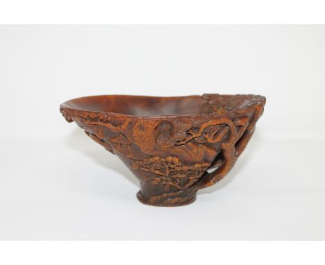A Chinese carved rhinoceros horn libation cup, late Qing period, of warm-toffee tone, the vessel finely carved externally in 