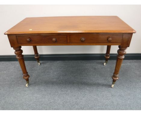 An early Victorian mahogany writing table, fitted two drawers, on turned legs terminating in ceramic castors, width 117cm. CO