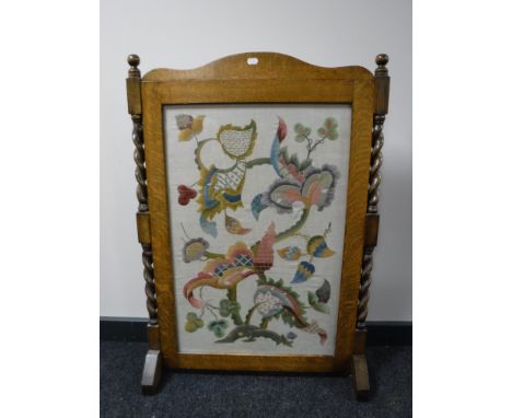 An Edwardian oak fire screen with embroidered panel, width 64cm. 