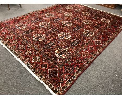 A Bakhtiari carpet, West Persia, of traditional design on red ground, 390 cm x 306 cm.