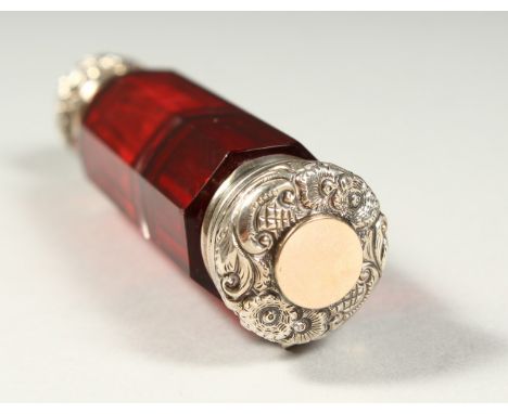 A VICTORIAN FACET CUT RUBY GLASS DOUBLE ENDED SCENT BOTTLE AND VINAIGRETTE with repousse silver ends. 10cms long.