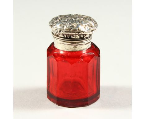 A SMALL VICTORIAN FACET CUT RUBY TINTED GLASS OCTAGONAL SCENT BOTTLE with repousse silver top. 4cms high x 2.5cms diameter.