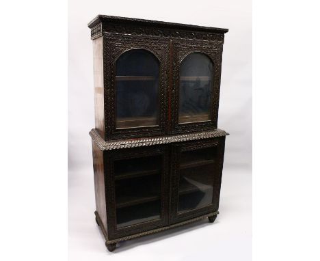 A GOOD 19TH CENTURY ANGLO INDIAN PADAUK WOOD CUPBOARD BOOKCASE, with lancet carved cornice, a pair of arched glazed doors enc