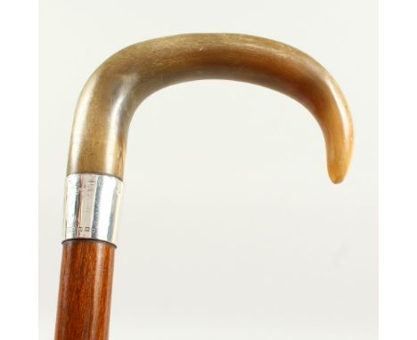 A WALKING STICK with Rhino curving handle and silver band. London 1921. 2ft 10ins long.